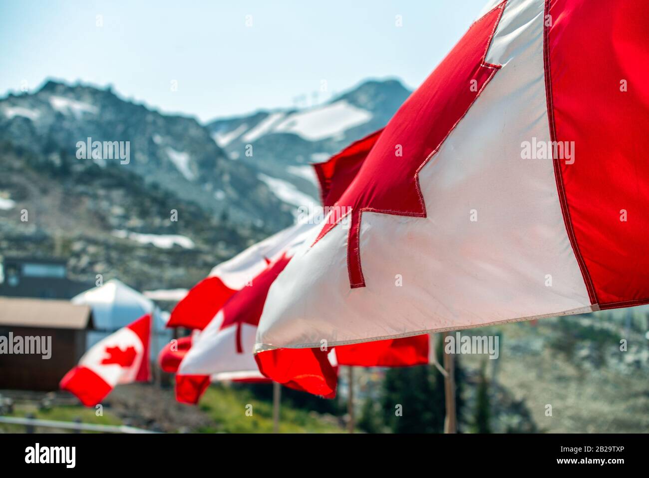 Bandiera del Canada ondeggiante al vento in scenario di montagna. Foto Stock