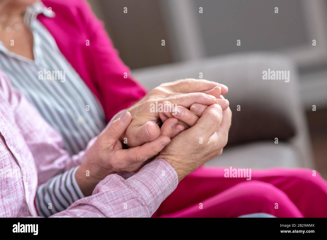 Uomo e donna seduti sul divano che si tengono le mani Foto Stock