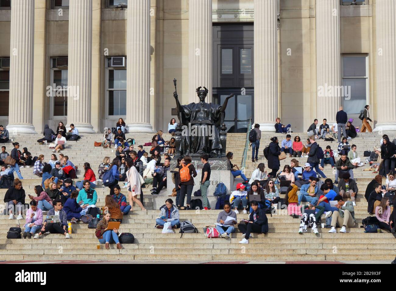 Gli studenti (e Alma Mater) si rilassano sui gradini della vecchia Columbia University Library in una calda giornata invernale, il 24 febbraio 2020, New York, NY. Foto Stock