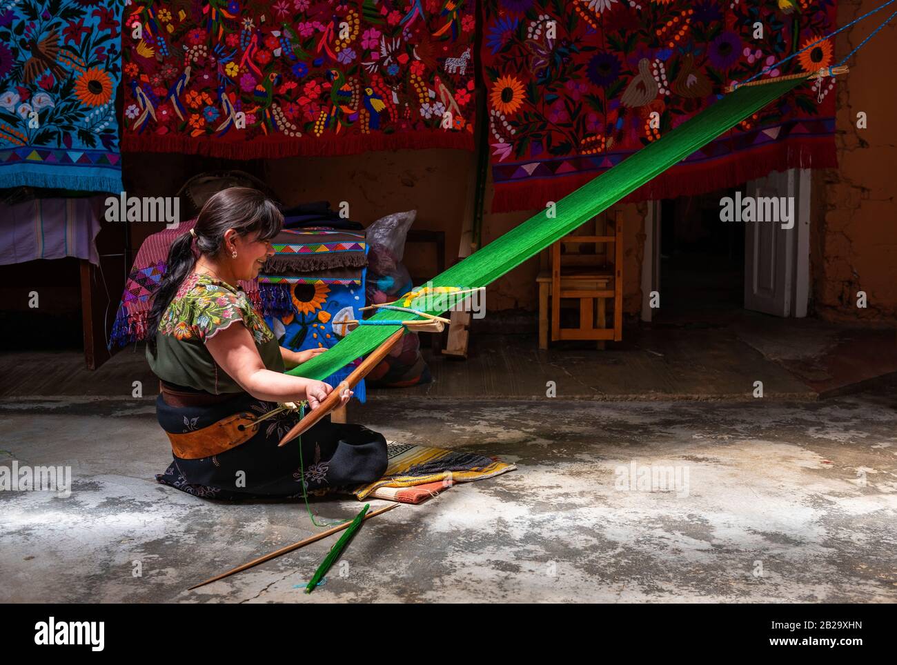 Una donna Tzotzil Maya che tessitura un tessile con la tecnica posteriore del telaio della cinghia nella regione di San Cristobal de las Casas in Zinacantan, Chiapas, Messico. Foto Stock