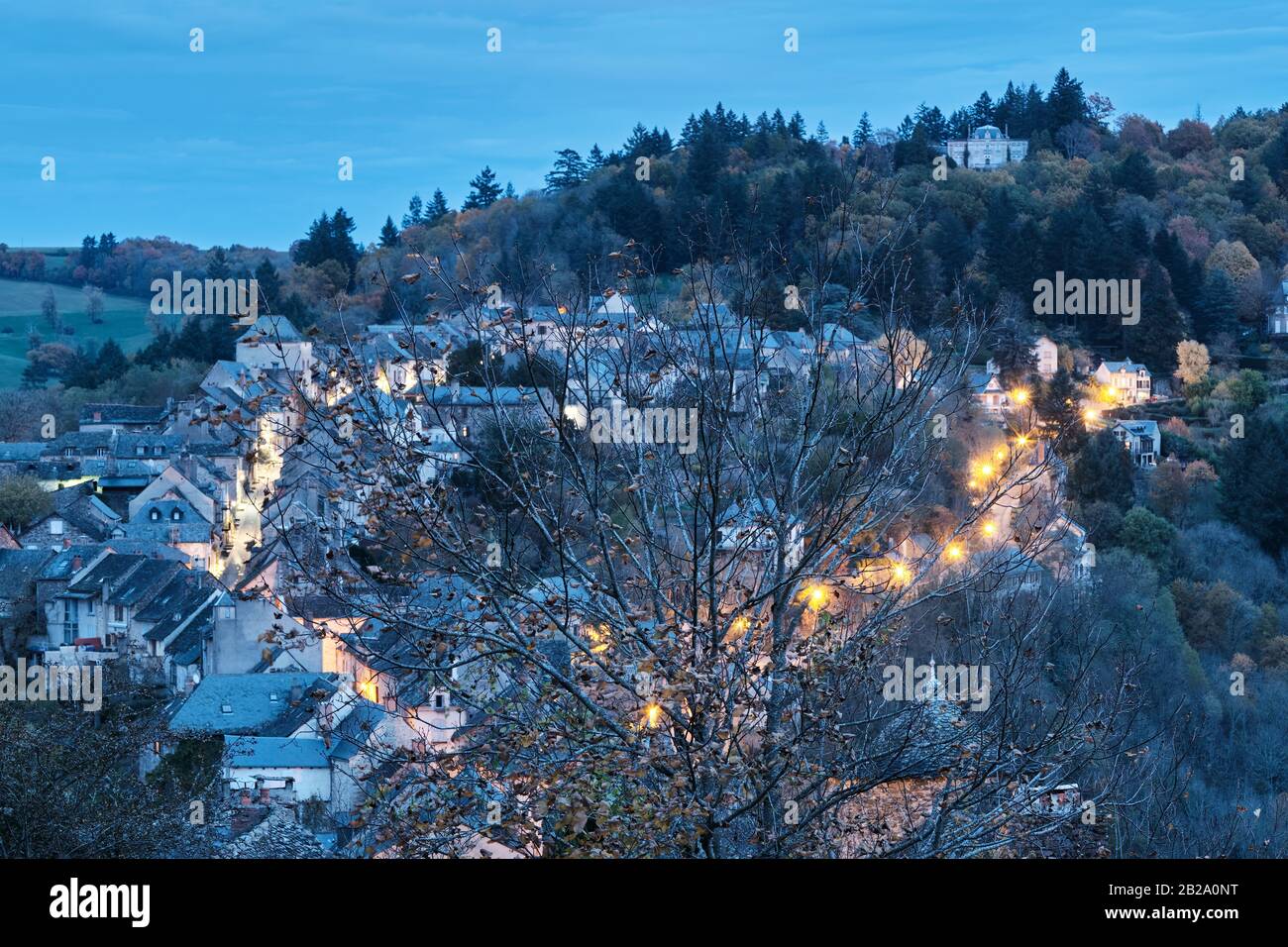 Piccola città illuminata e avvolta da un albero in primo piano, Najac, Francia Foto Stock