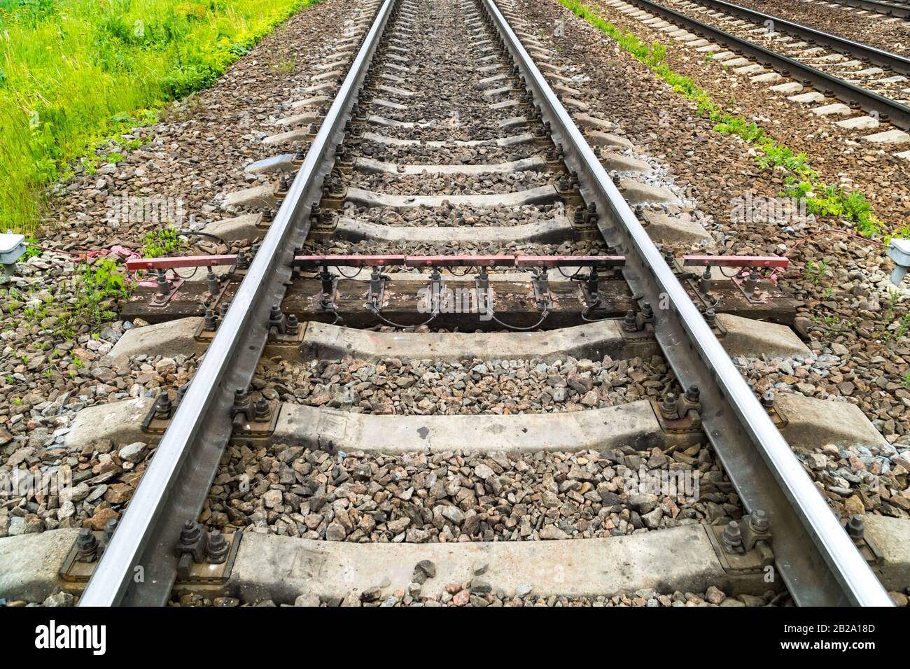 Vecchia ferrovia arrugginita. Tra le traverse in cemento c'è una traversina in legno con sensori di misura Foto Stock