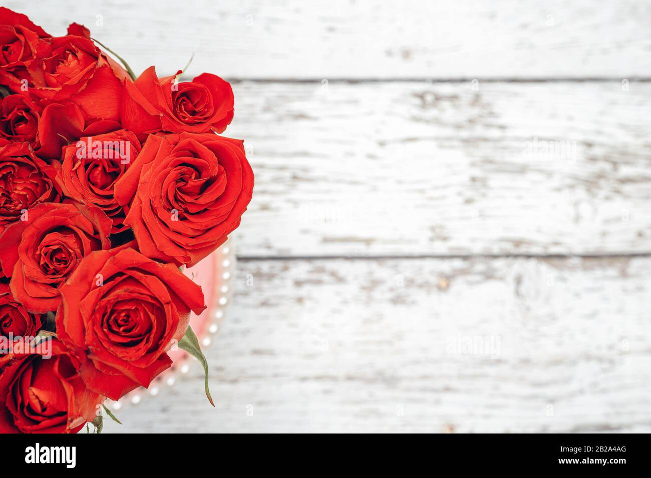 Un bouquet di rose scarlatto per il concetto di ornamenti di San Valentino con sfondo di legno bianco. Amore e concetto romanticismo Foto Stock