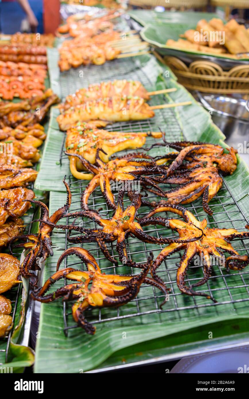 Polpo barbequed con spiedini di pollo in una stalla di cibo di strada, Bangkok, Thailandia Foto Stock
