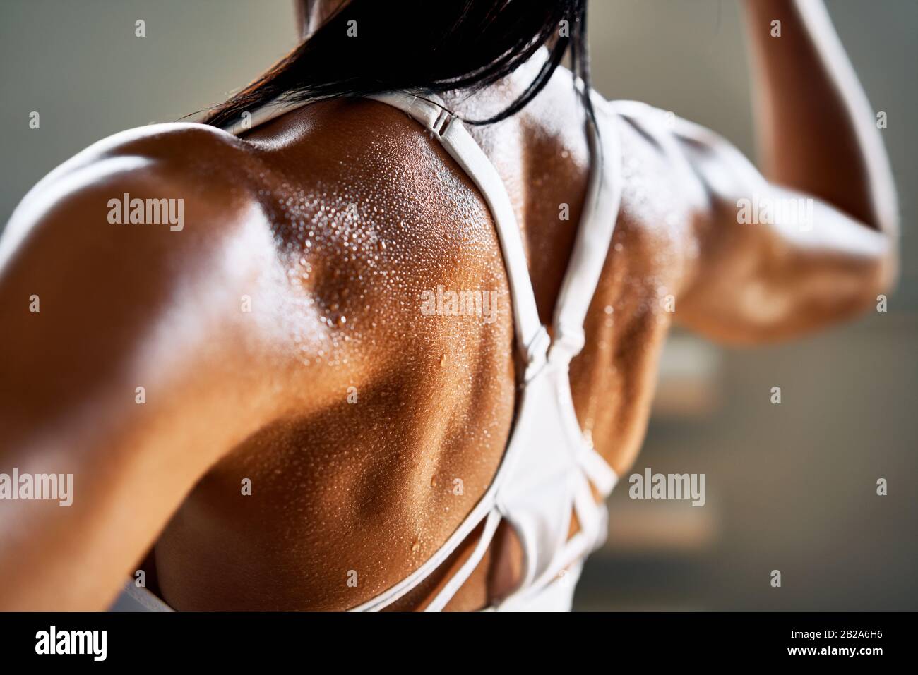 Primo piano della donna con la flessione dei muscoli nel sudore sulla pelle dopo l'allenamento. Bodybuilder femminile con bicipite perfetto Foto Stock