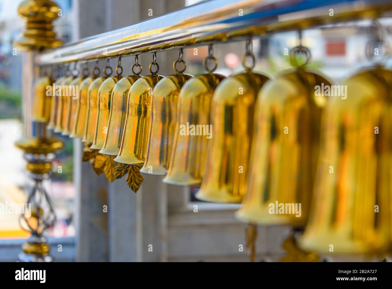 Fila di campane di ottone suonano i suoni del vento a Wat Songkhram, Bangkok, Thailandia Foto Stock