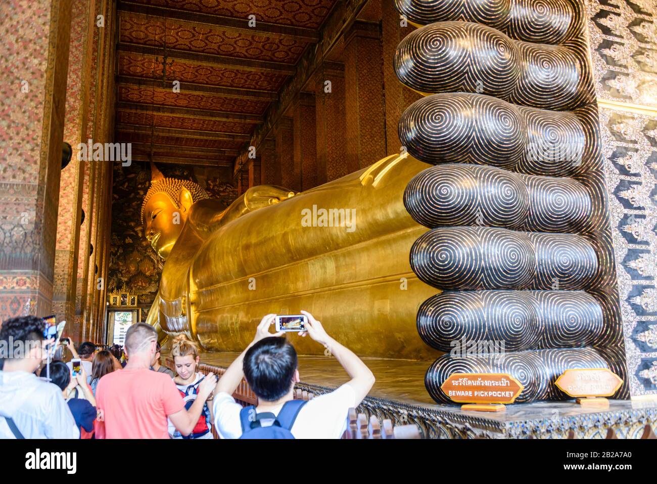 Il turista scatta fotografie ai piedi del Buddha reclinato dorato più antico del mondo a Wat Pho, Bangkok, Thailandia Foto Stock