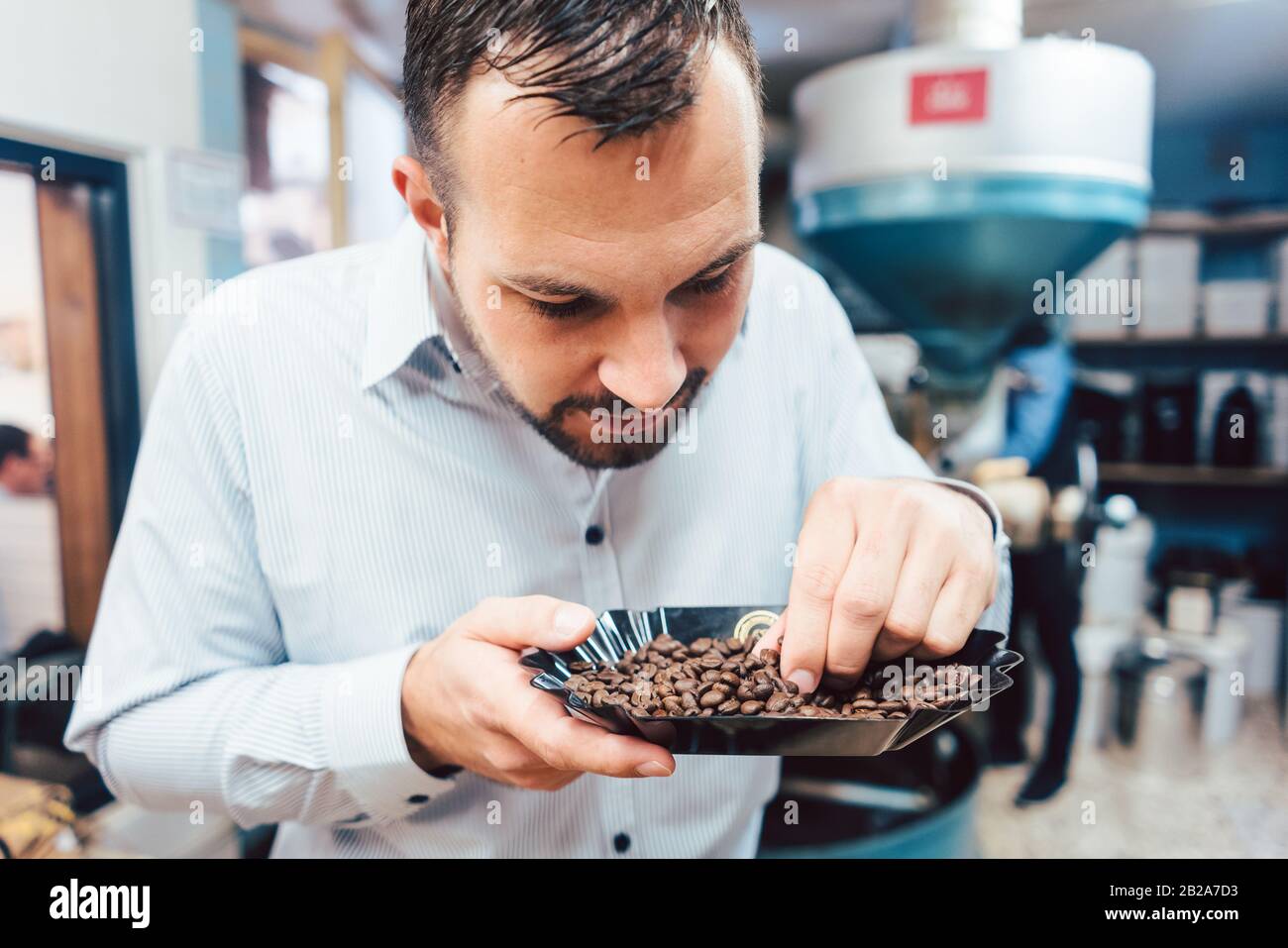 Uomo con chicchi di caffè appena tostati Foto Stock