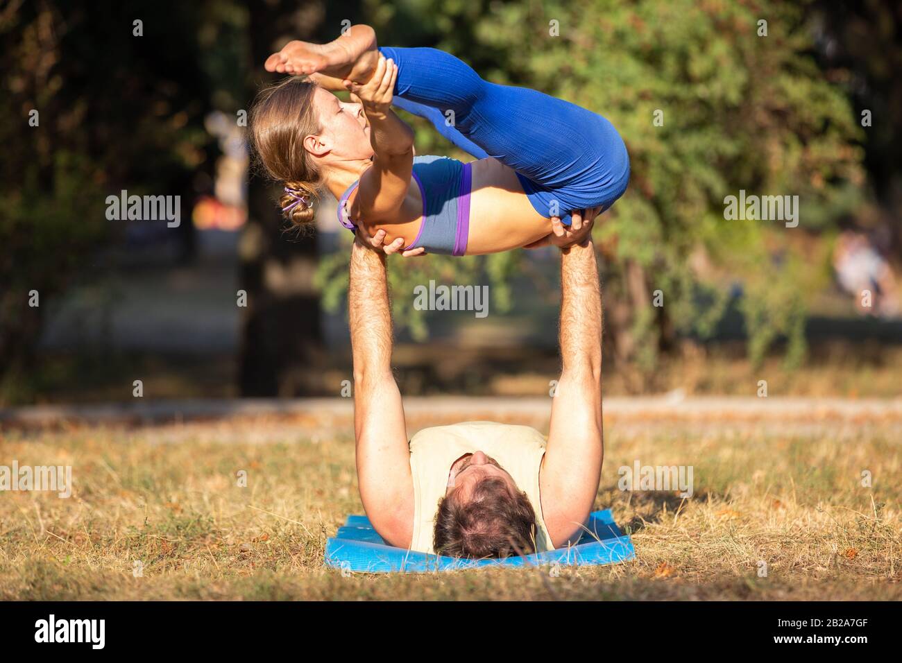 Coppia di Acroyoga che si equilibrano sulle mani nel parco. Yoga uomo e donna praticare l'acrobyoga in estate Foto Stock