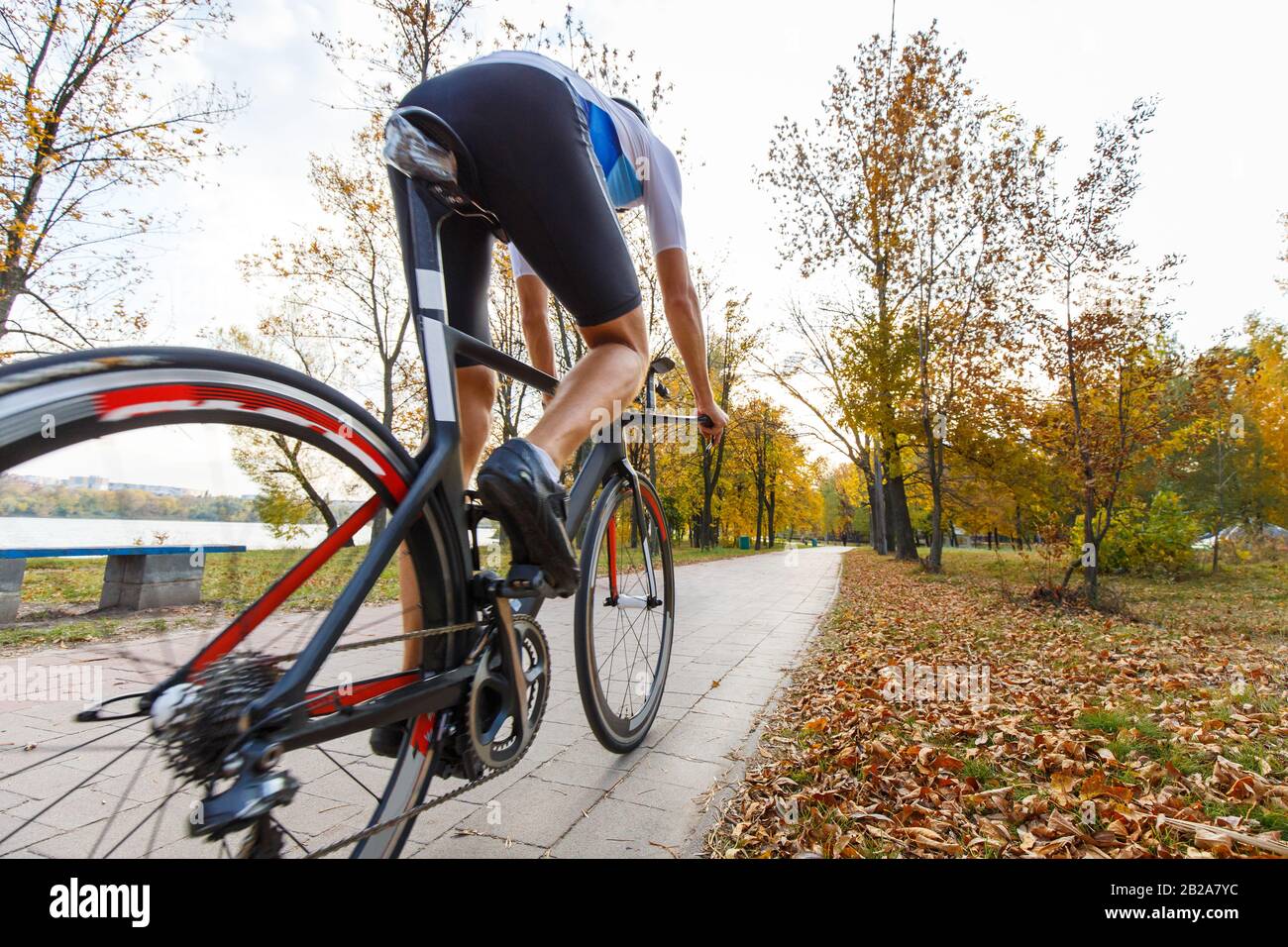 Giovane triatleta ciclista riding bike nel parco d'autunno. Ampio angolo di visione con spazio di copia Foto Stock