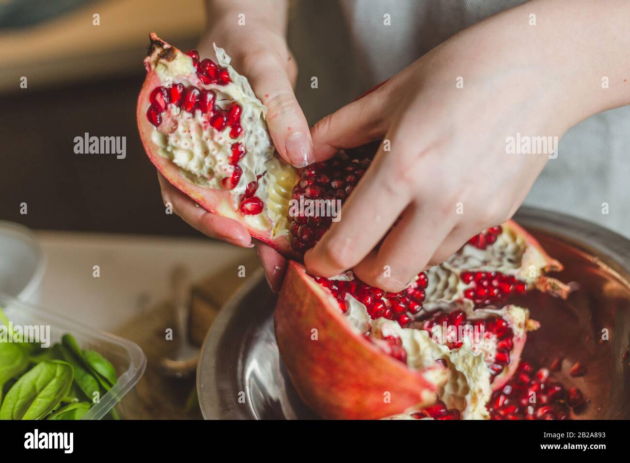 Cucina amatoriale - primo piano le mani femminili togliere il grano dal melograno Foto Stock