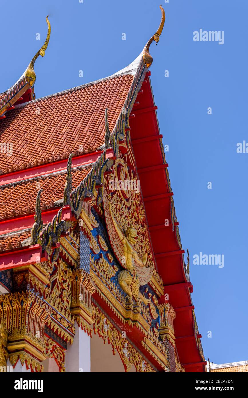 Decorazioni ornate sul tetto e statue dorate al tempio buddista Wat Mongkhon Nimit, nella città vecchia di Phuket, Thailandia Foto Stock