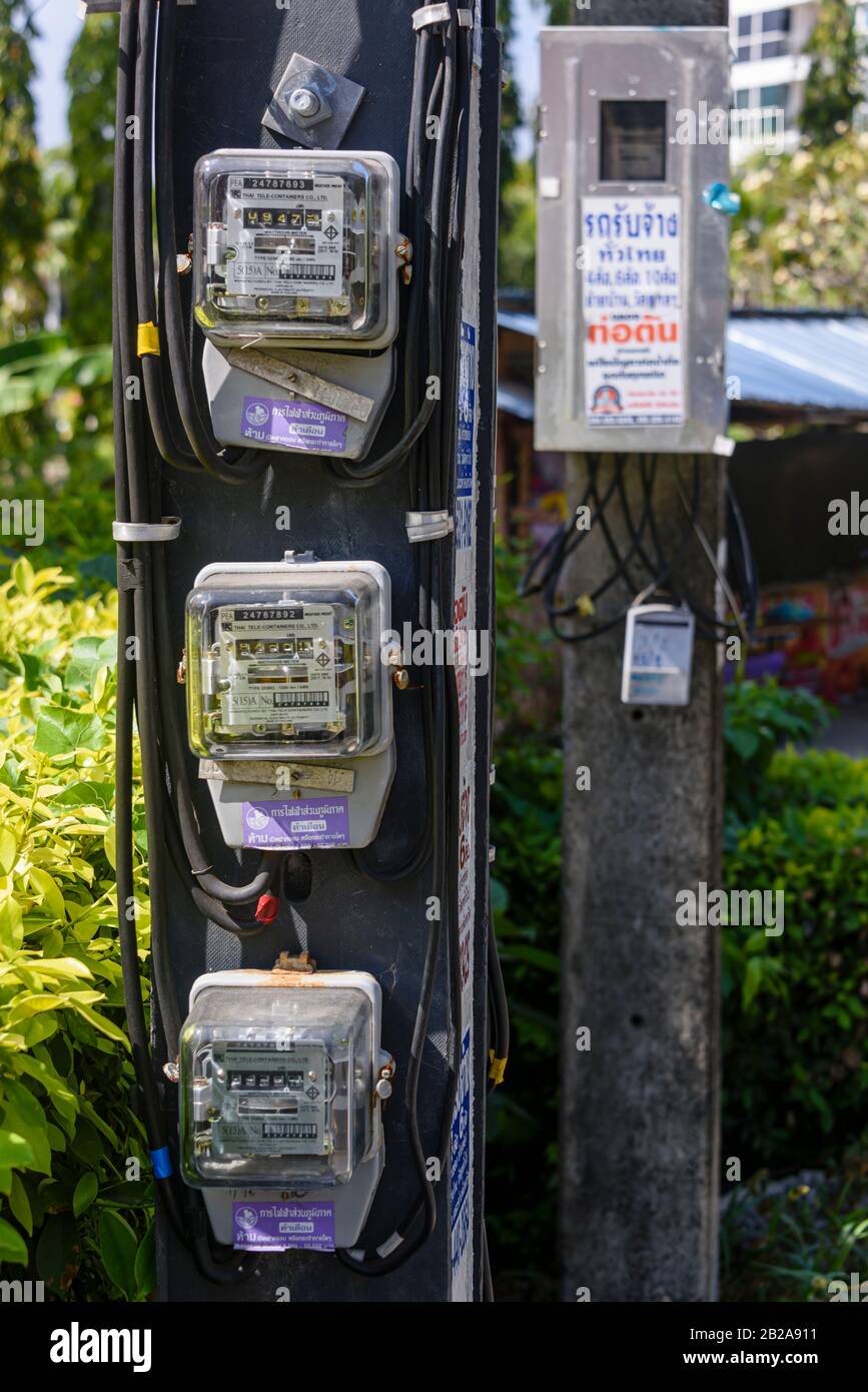 Contatori elettrici e cavi elettrici collegati a un polo elettrico esterno in Thailandia Foto Stock