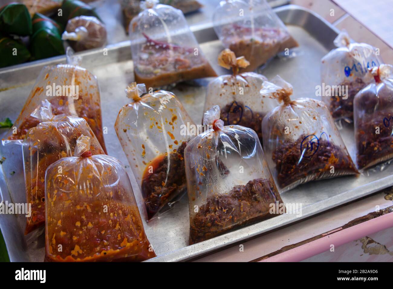 Sacchetti di plastica riempiti con paste tradizionali tailandesi di cucina in vendita in una stalla di mercato, Phuket, Thailandia Foto Stock