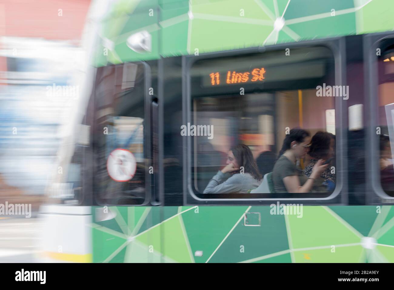 Un'immagine leggermente offuscata di un tram in movimento, con una giovane donna da sola e che guarda verso l'esterno una finestra in un umore triste Foto Stock