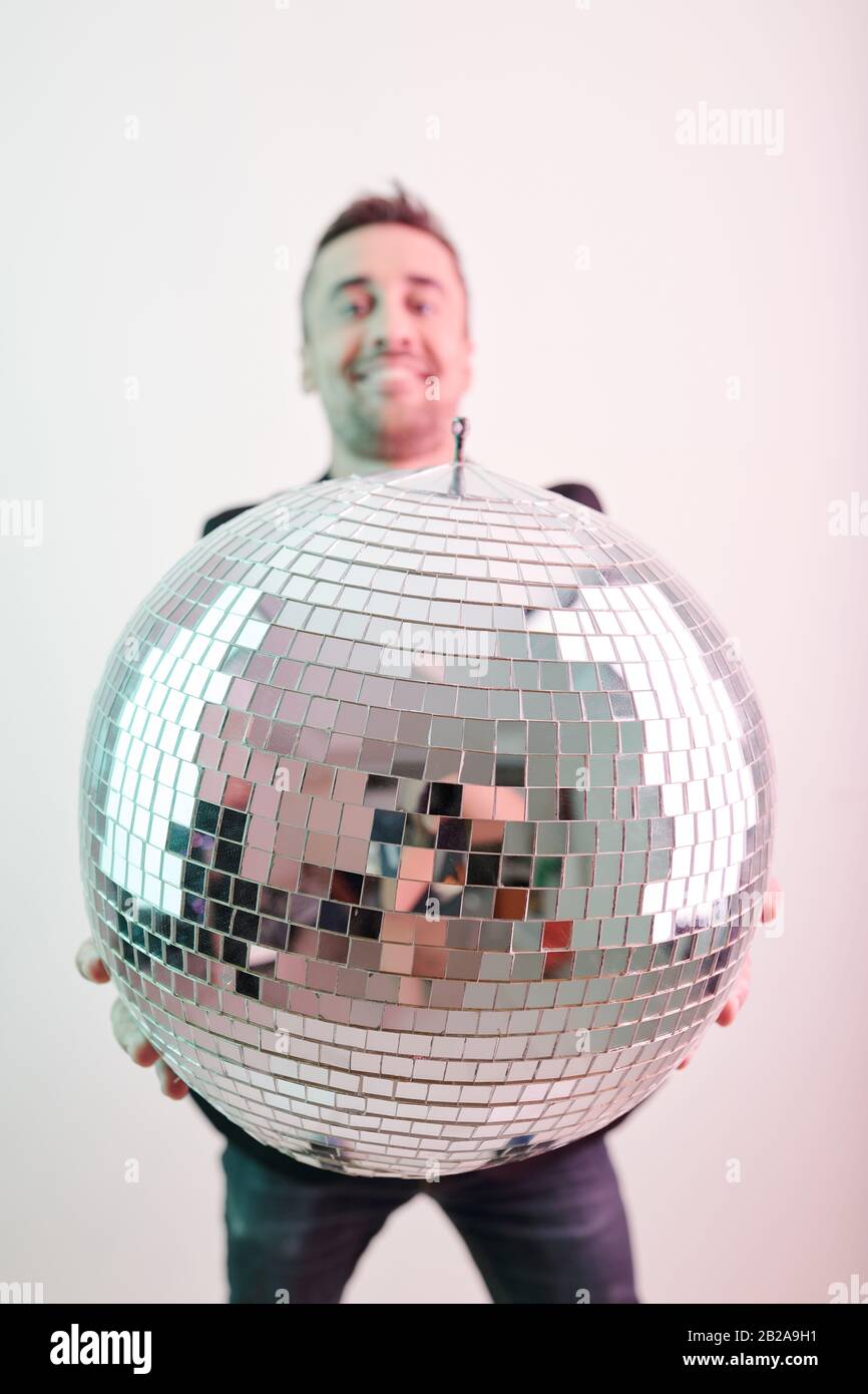Giovane eccitato che tiene una grande palla da disco lucido Foto Stock