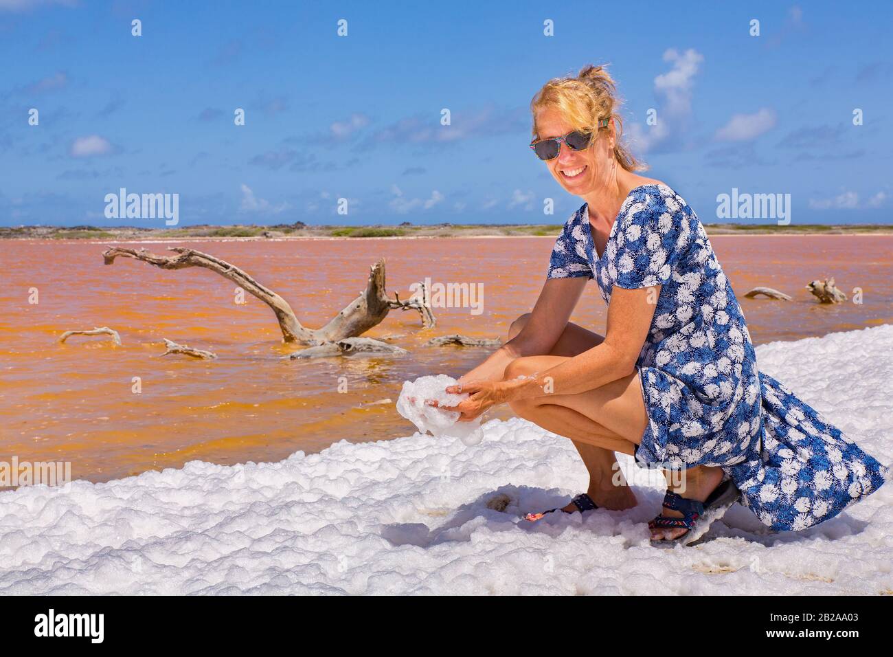 La donna olandese tiene schiuma bianca vicino al lago di sale arancione su Bonaire Foto Stock