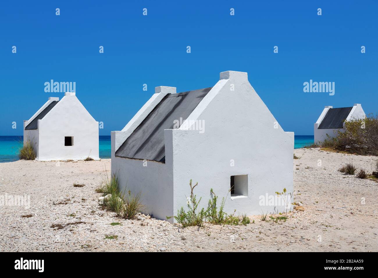 Tre slave case bianche sulla costa con oceano blu sull'isola Bonaire Foto Stock