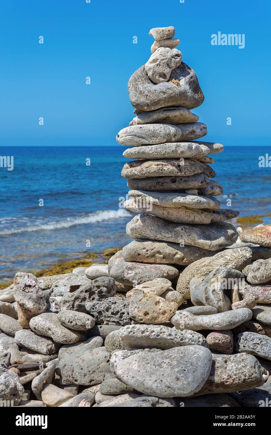 Stones accatastati sulla spiaggia con il mare blu sull'isola Bonaire Foto Stock