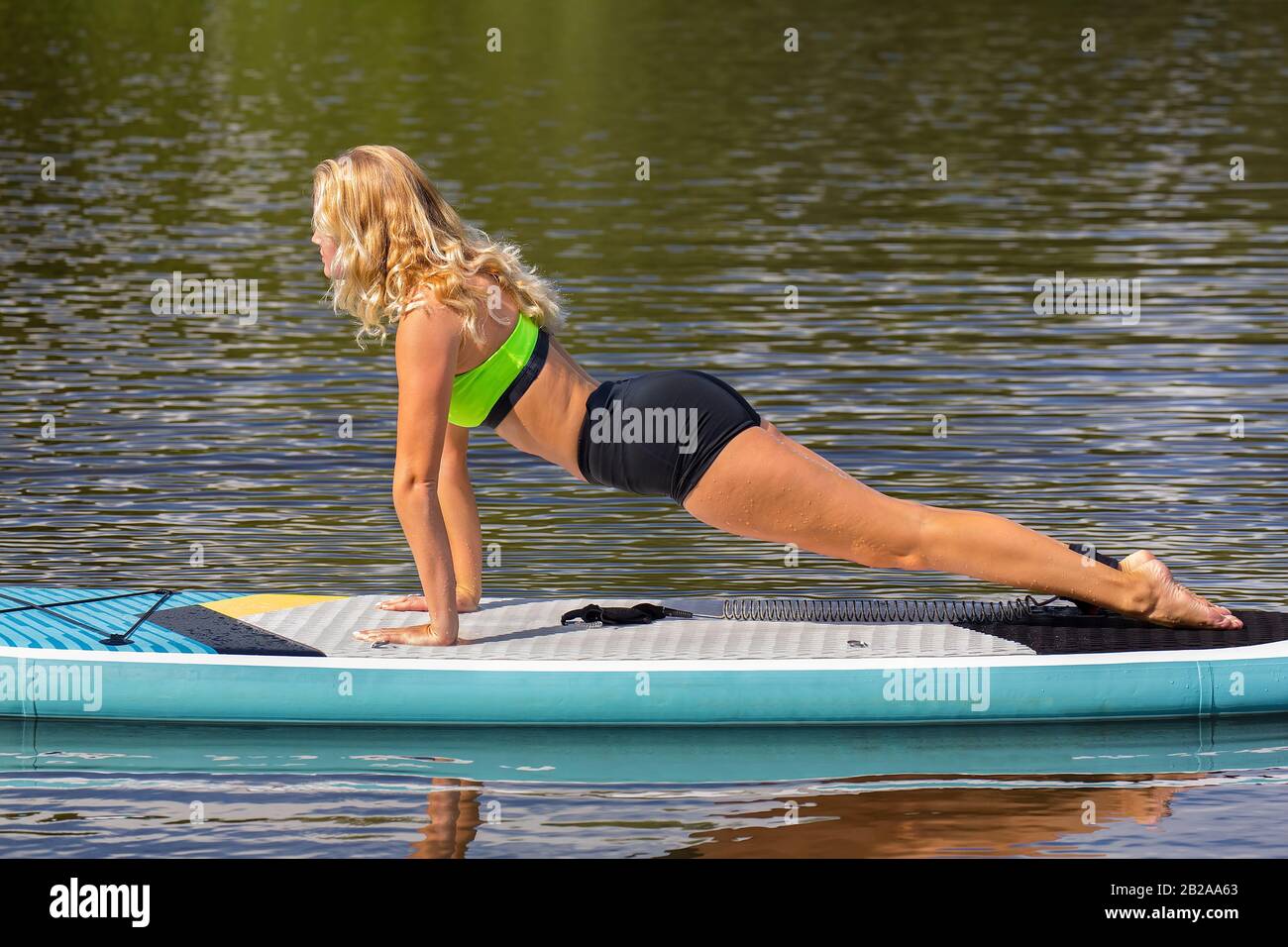 Giovane donna olandese planking in avanti sul SUP a acqua del lago Foto Stock