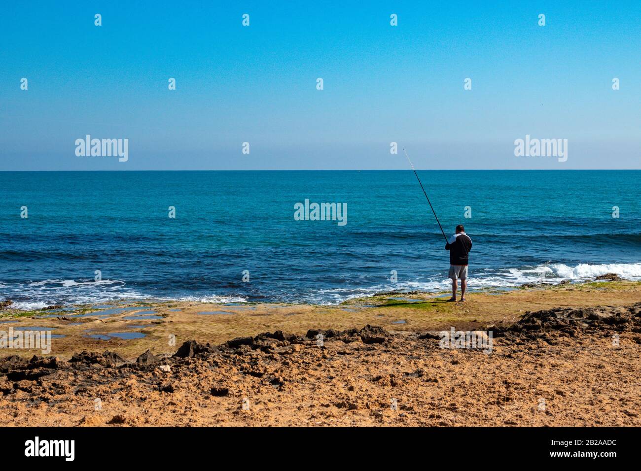 Solitario pescatore sulla costa mediterranea a Torrevieja, Costa Blanca, Spagna Foto Stock