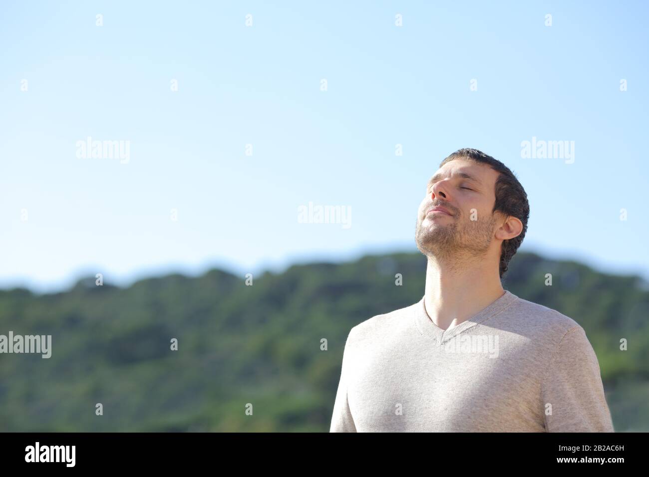 Uomo rilassato respirare aria fresca vicino alle montagne con un cielo blu sullo sfondo Foto Stock