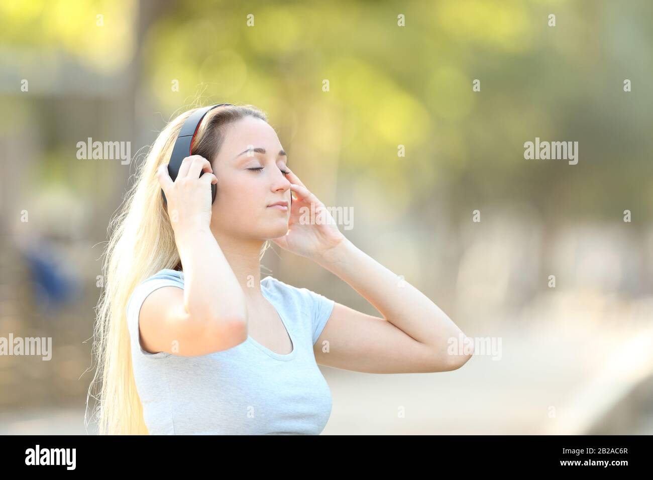 Concentrato ragazza adolescente ascolto di musica con uno sfondo parco in estate Foto Stock