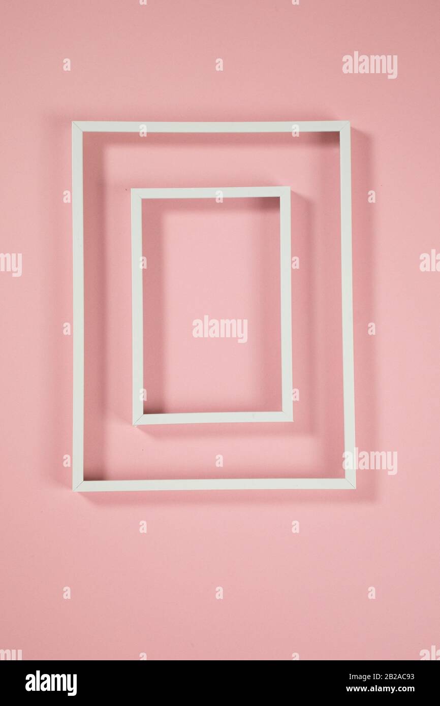Cornici bianche su sfondo rosa e alcune ombre Foto Stock