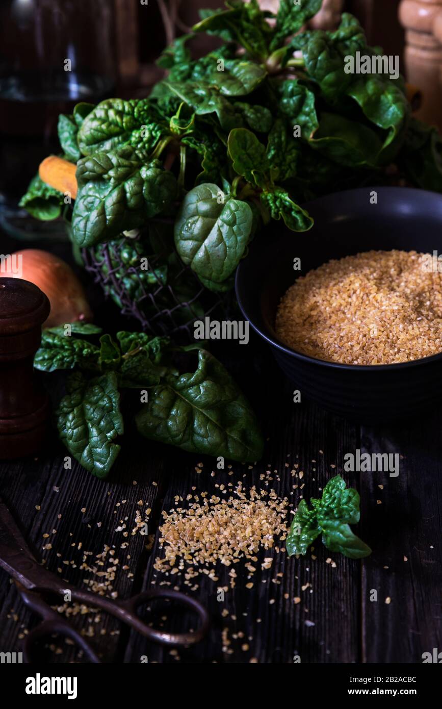 Spinaci, cipolla e grano bulgur su un tavolo di legno Foto Stock