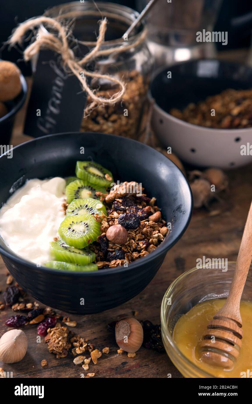 Prima colazione granola con miele, noci, yogurt e kiwi frutta Foto Stock