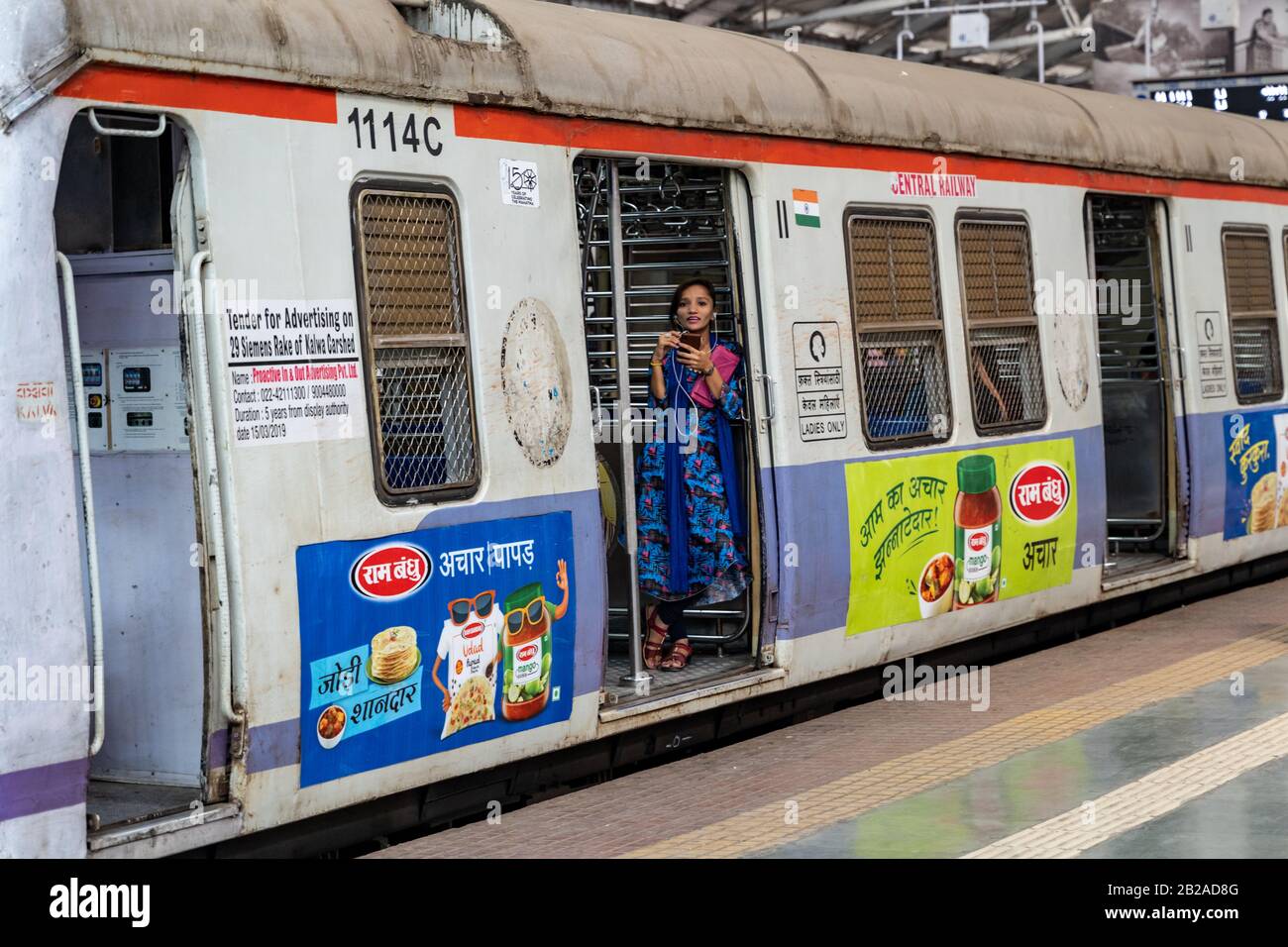 Mumbai, India - 29 febbraio 2020: La giovane donna indiana si trova nella porta della ferrovia con un telefono a Chatrapati Shivaji Terminus precedentemente conosciuto come Foto Stock