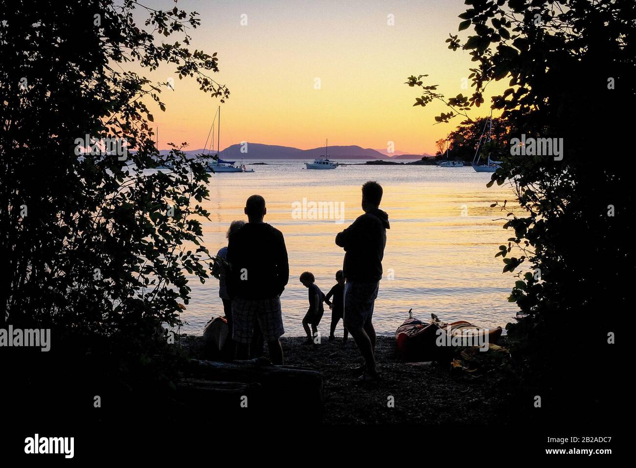 Silhouette di una famiglia andando in kayak al tramonto, San Juan Island, Washington Bay, Stati Uniti Foto Stock
