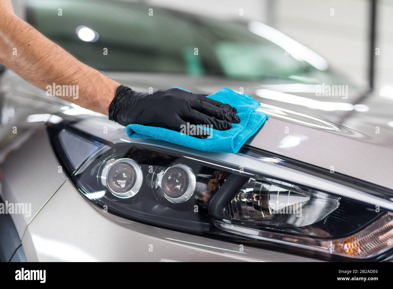 Dettagli auto - l'uomo detiene la microfibra in mano e leviga la vettura. Messa a fuoco selettiva. Foto Stock