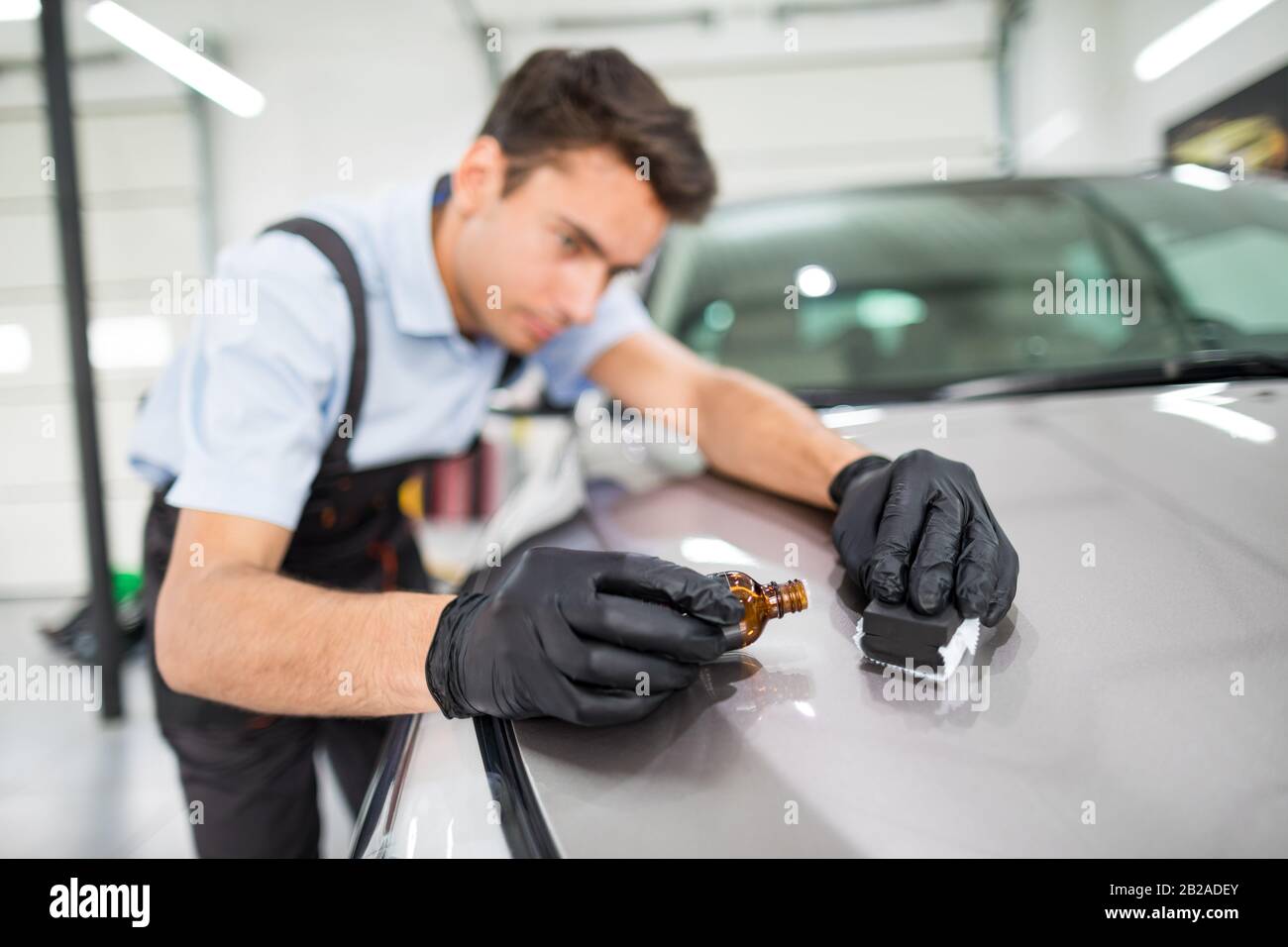 Dettagli auto - l'uomo applica il rivestimento protettivo nano alla vettura. Messa a fuoco selettiva. Foto Stock