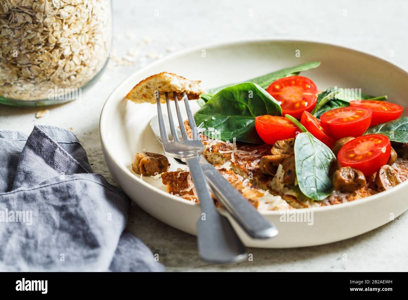 Frittella di farina d'avena con formaggio, pomodori e spinaci. Sana colazione fitness. Foto Stock