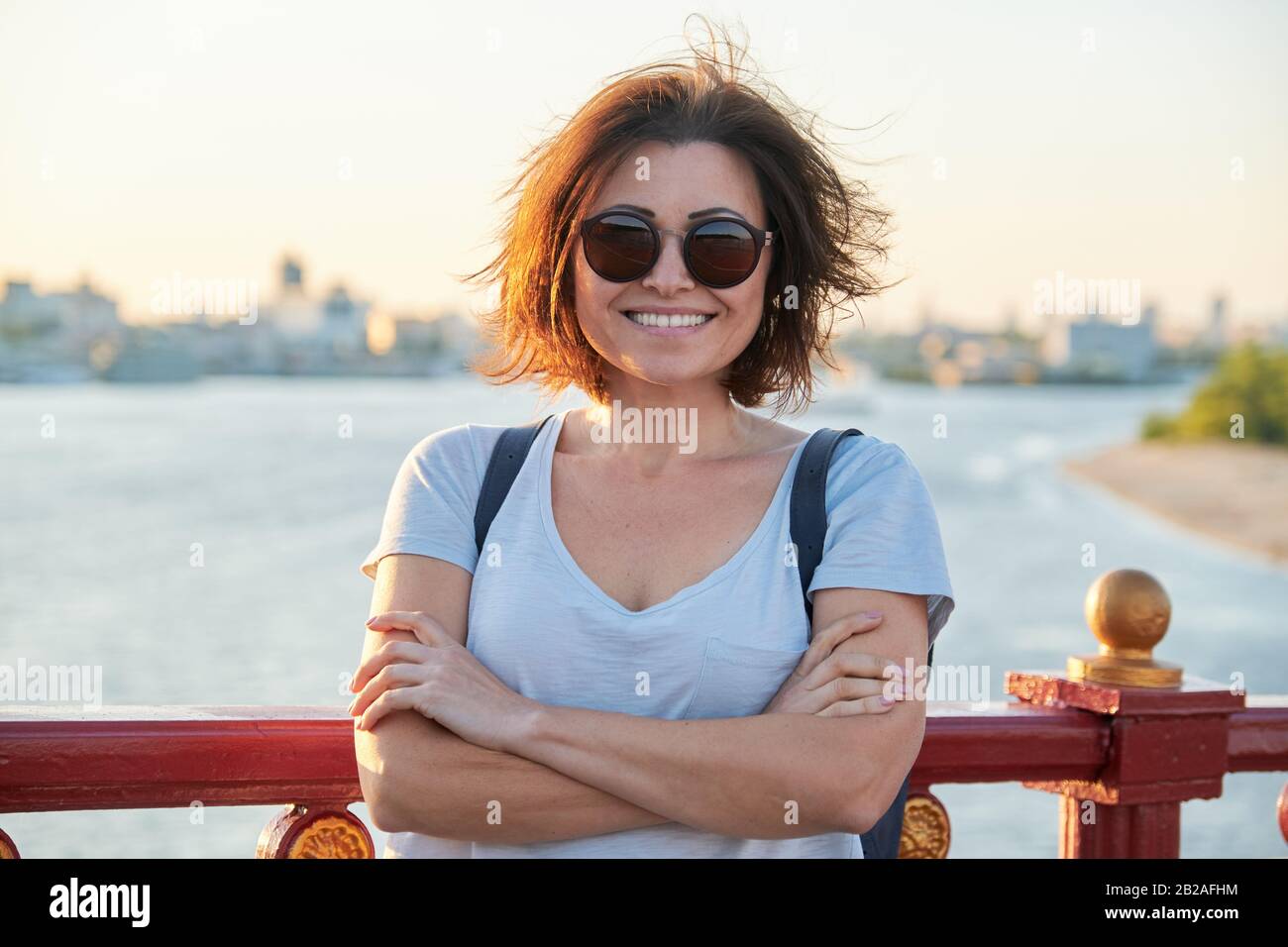 Ritratto all'aperto di donna sorridente di mezza età positiva in occhiali da sole Foto Stock