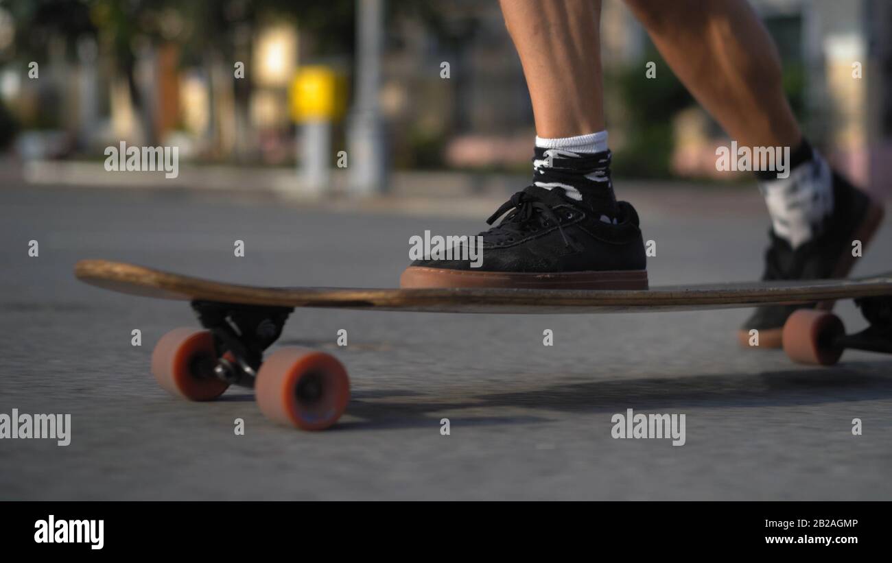 Le gambe dello skateboarder si pedalano a bordo sulla strada della città. Foto Stock