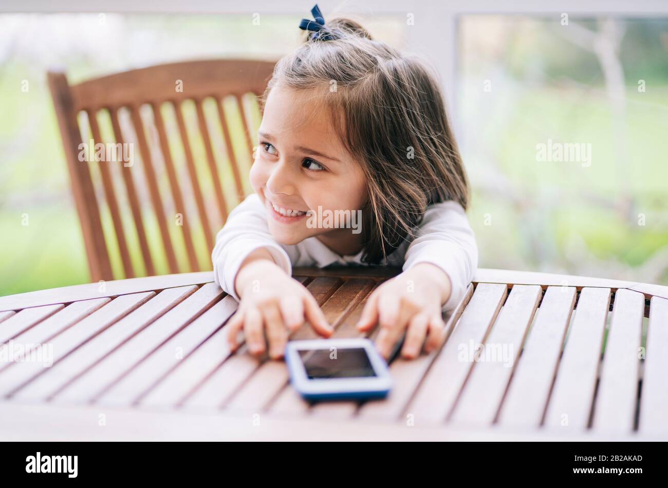 Una bambina usa lo smartphone del telefono cellulare a casa Foto Stock