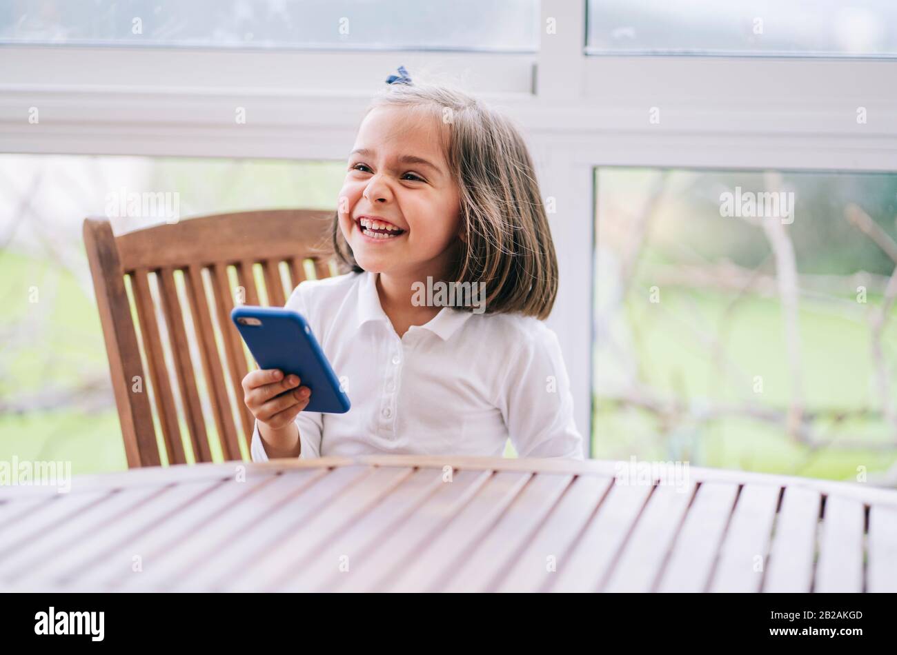 Una bambina usa lo smartphone del telefono cellulare a casa Foto Stock
