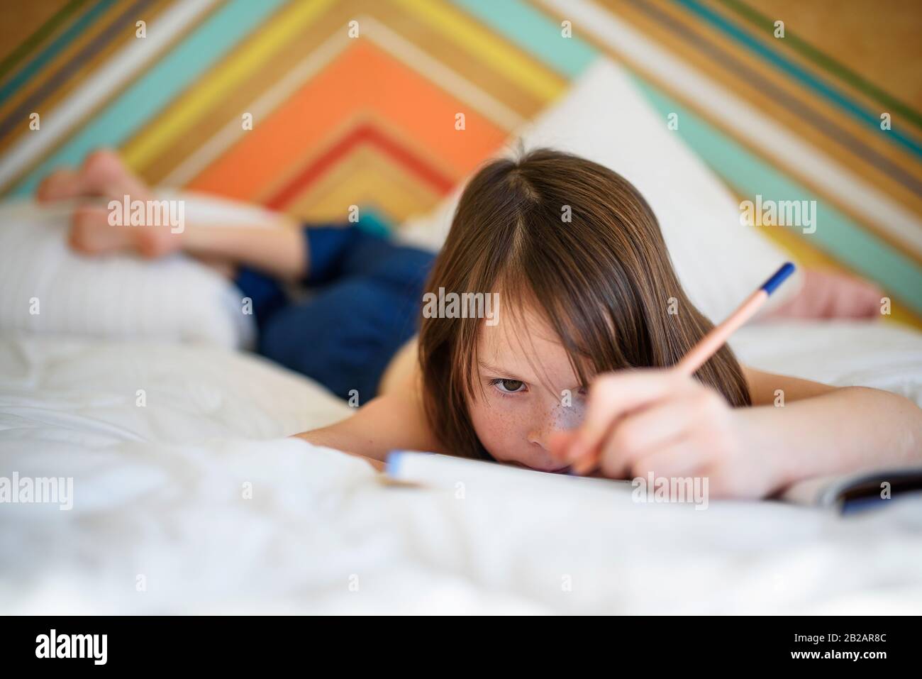 Ritratto di una ragazza sdraiata sul suo letto facendo il suo lavoro Foto Stock