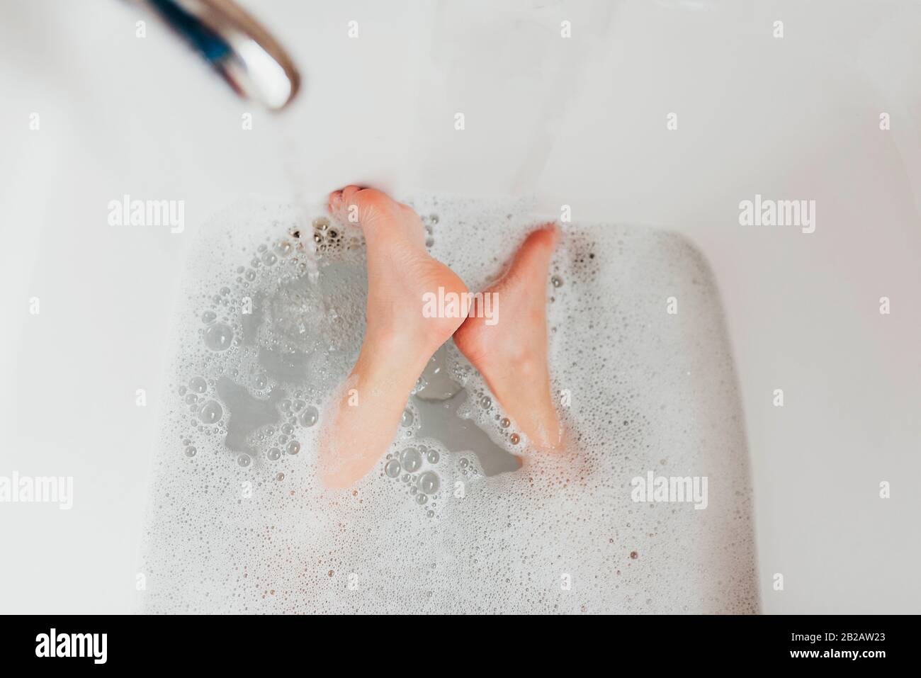 Primo piano dei piedi di un ragazzo in un bagno di bolle Foto Stock