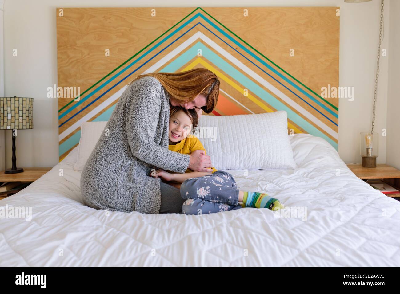 Madre felice e figlia seduta su un letto coccole Foto Stock