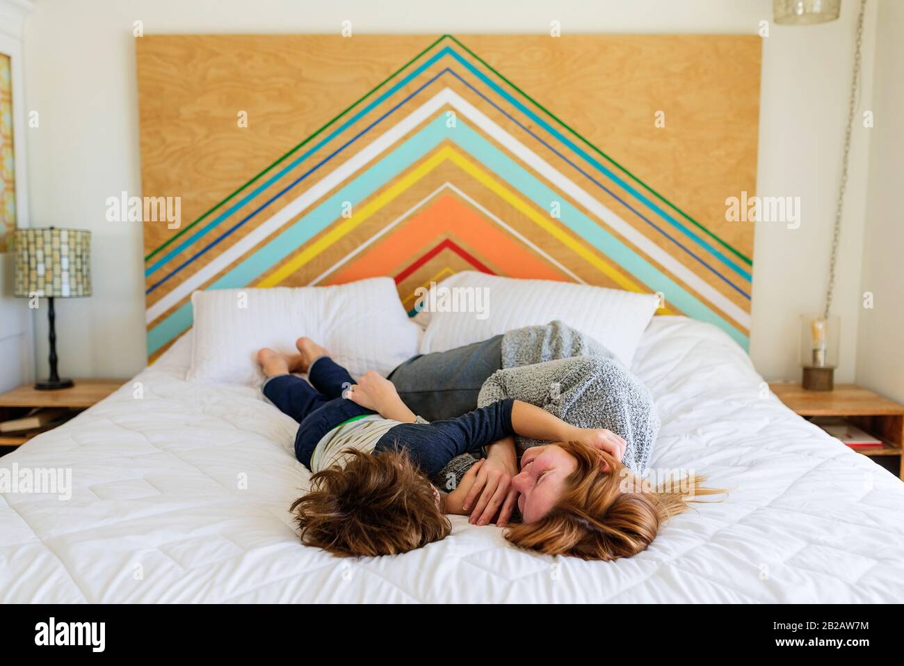 Madre felice e figlio sdraiati su un letto coccolante Foto Stock