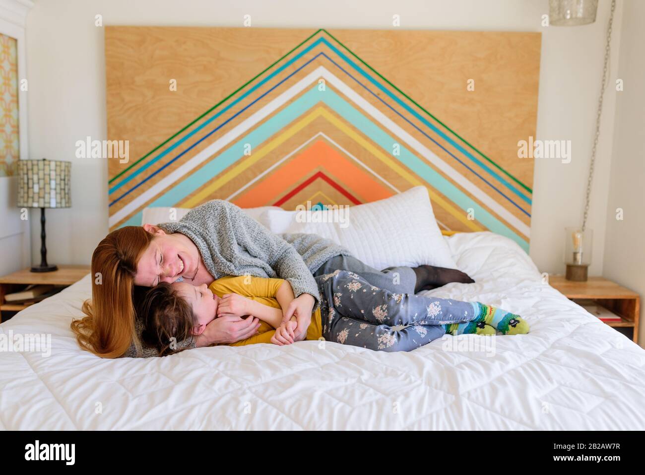 Madre e figlia sdraiata su un letto coccolante Foto Stock