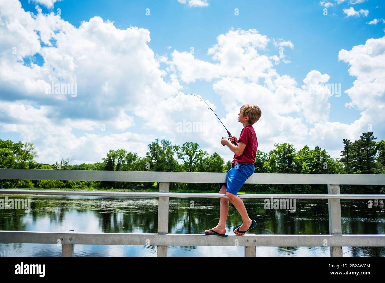 Ragazzo seduto su una recinzione su un molo di pesca, Stati Uniti Foto Stock
