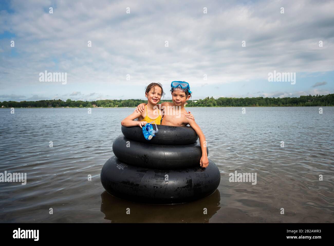 Ragazza e ragazzo in piedi all'interno di anelli gonfiabili in gomma in un lago, Stati Uniti Foto Stock