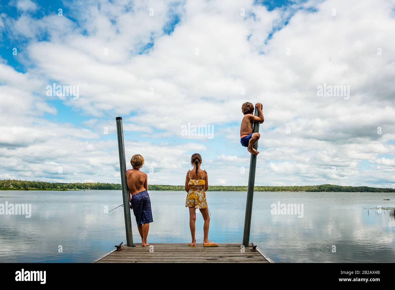 Tre bambini in piedi su un bacino di pesca e di messing circa, Stati Uniti Foto Stock