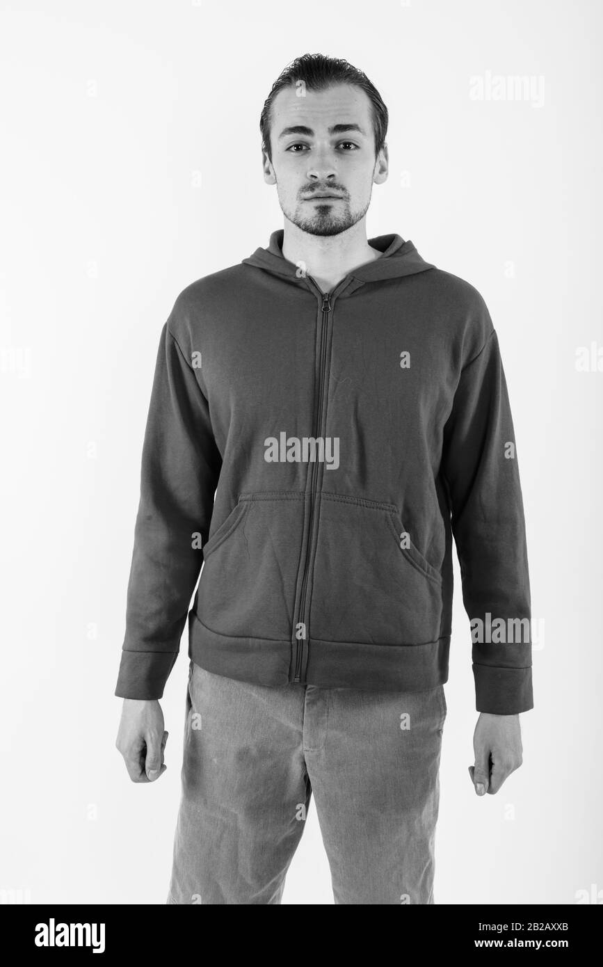 Studio shot del giovane uomo barbuto che indossa felpa con cappuccio rosso contro lo sfondo bianco Foto Stock