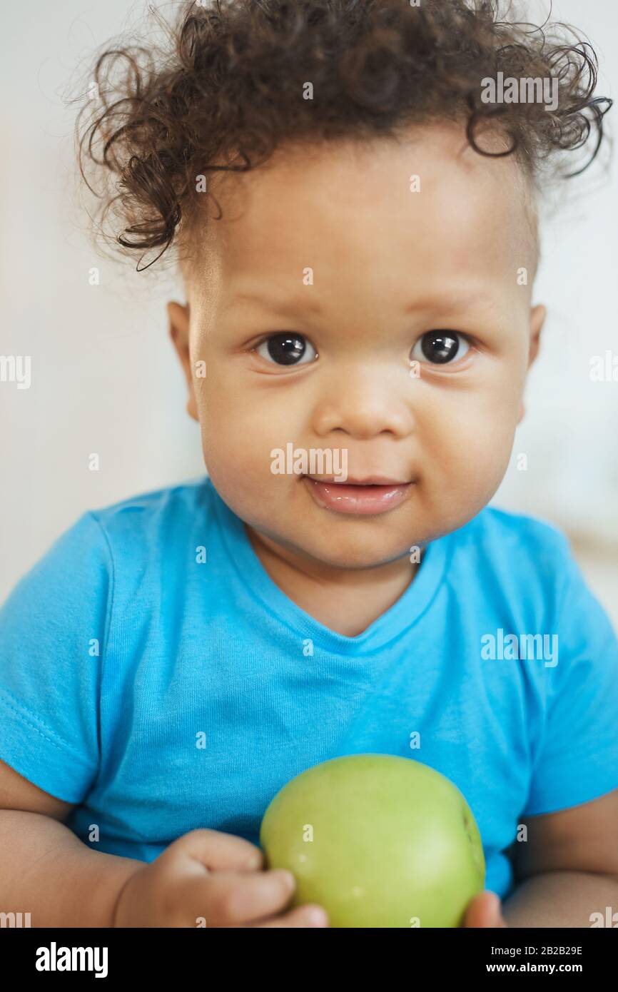 Ritratto verticale di cute afro-americano ragazzo tenendo mela verde e sorridendo alla macchina fotografica Foto Stock