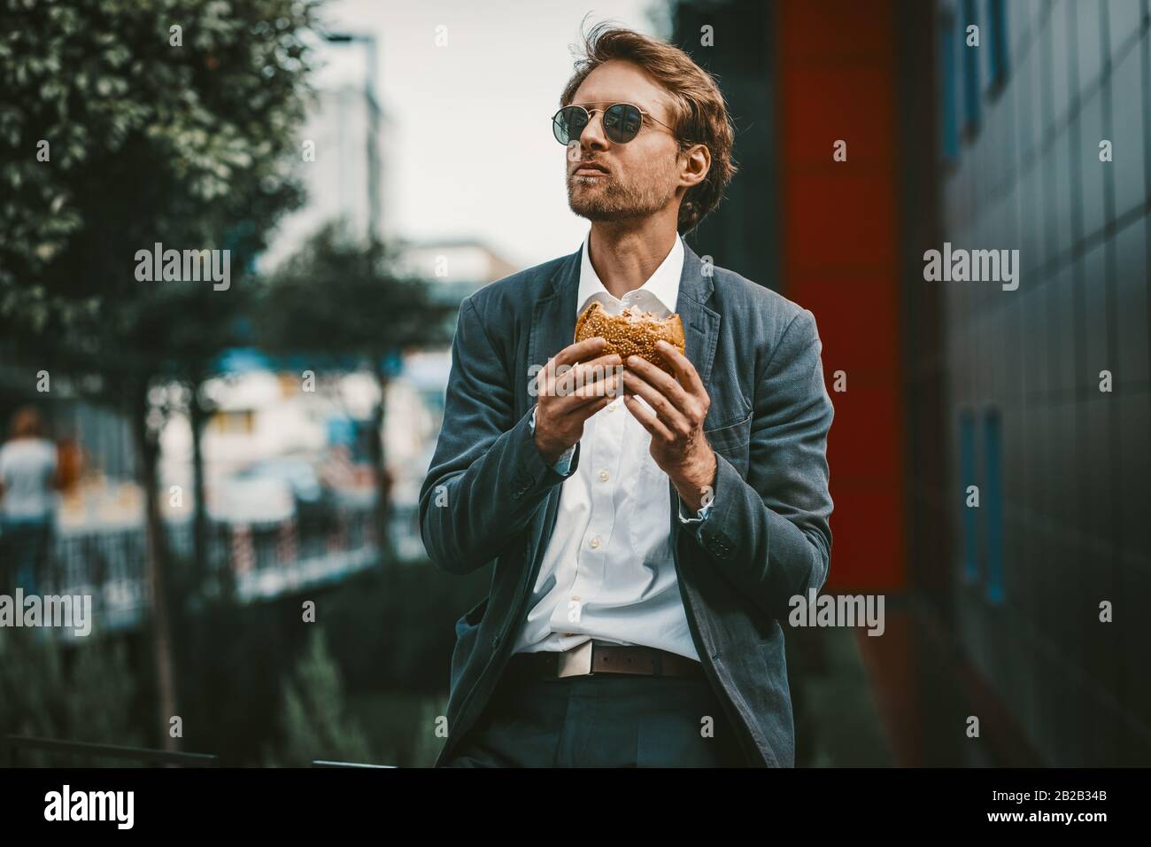 Giovane studente affamato che ha un hamburger in una pausa pranzo Foto Stock